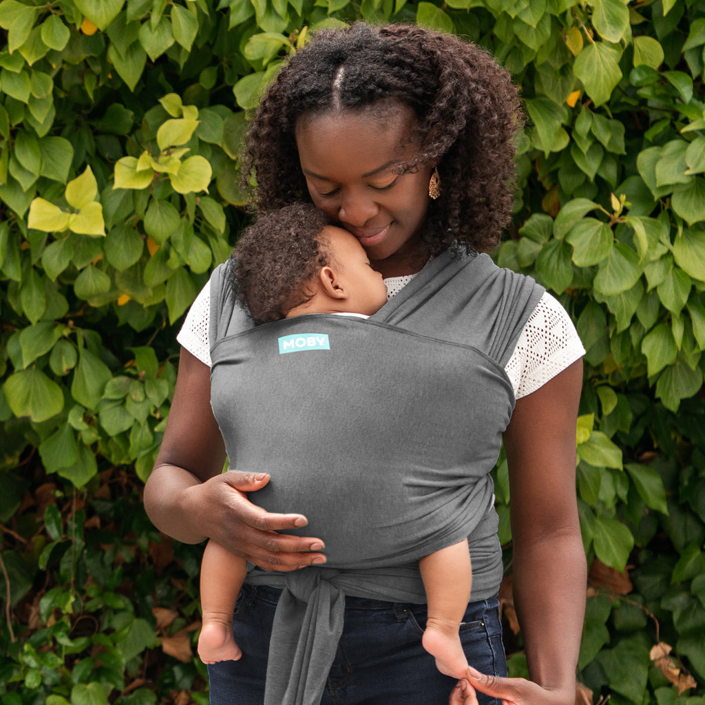 mom wearing baby in elements wrap in asphalt