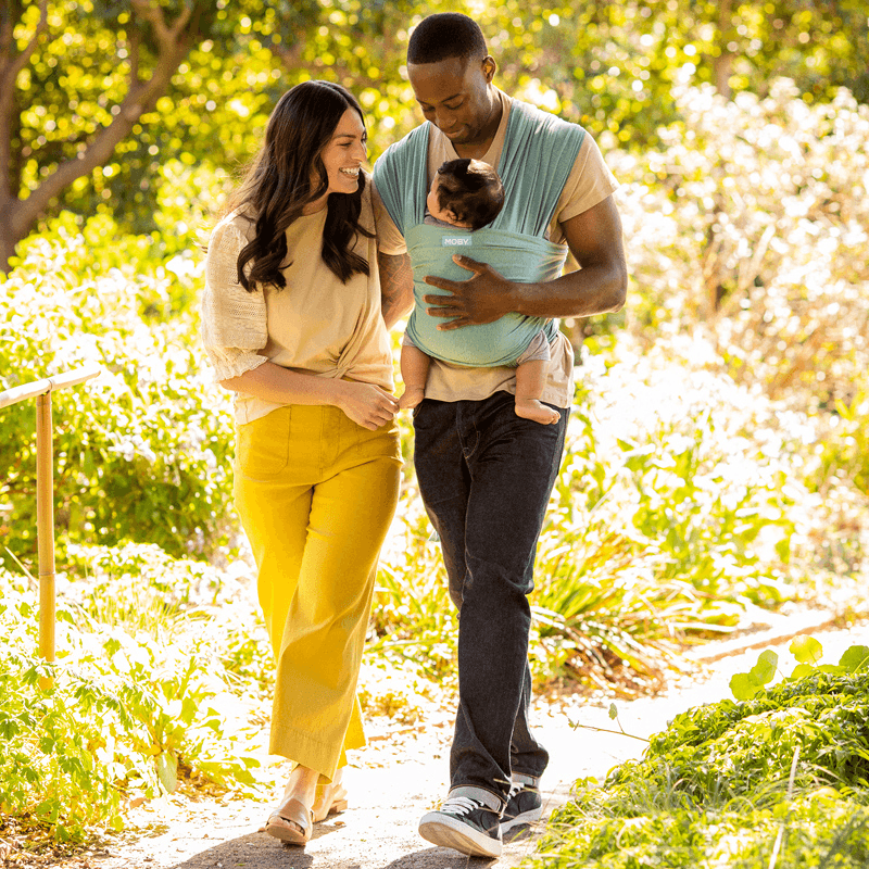 dad wearing baby in elements wrap in hydro while walking next to woman