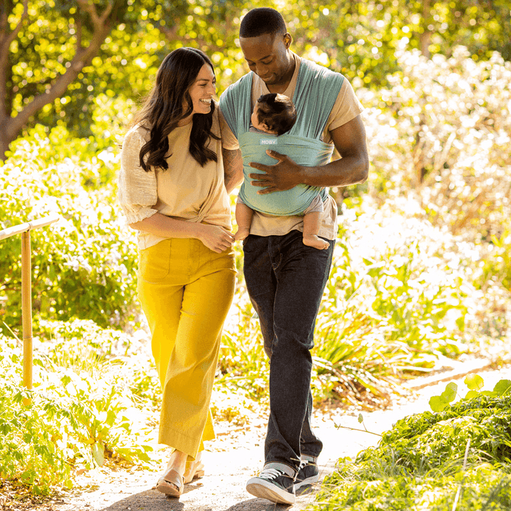 dad wearing baby in elements wrap in hydro while walking next to woman