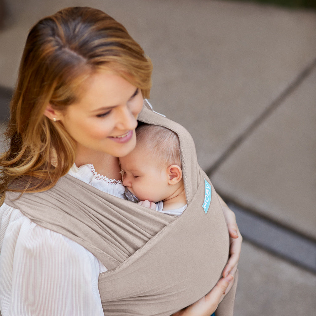 mom wearing baby in elements wrap in taupe