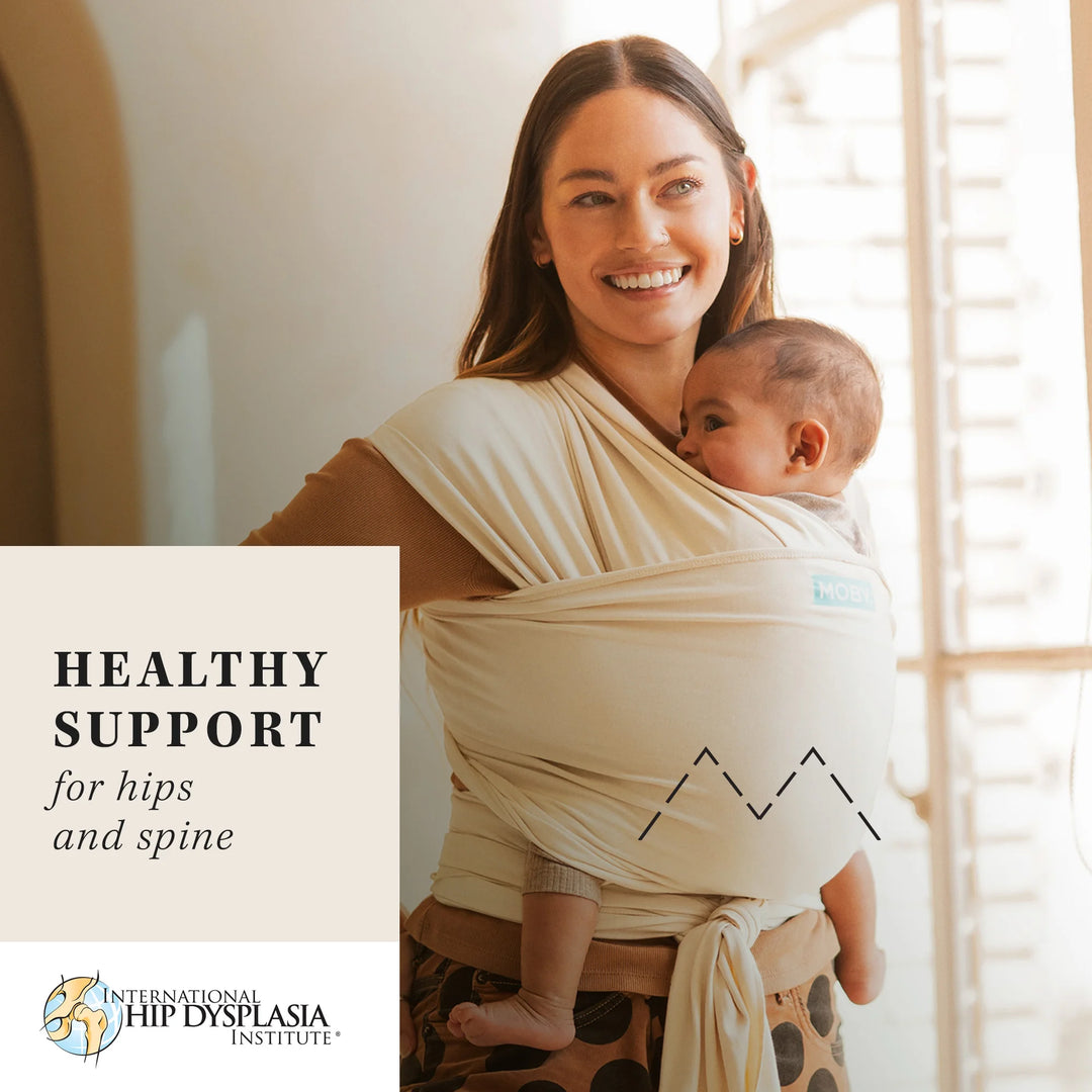 mom wearing baby in classic wrap in sand dollar. healthy support for hips and spine from the international hip dysplasia institute.