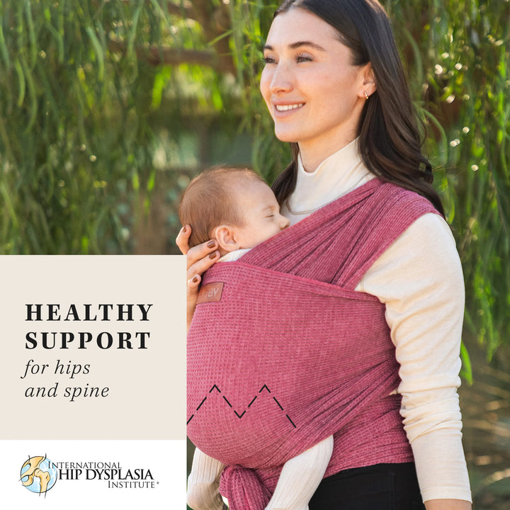 mom wearing baby in waffle knit wrap in desert rose. healthy support for hips and spine from the international hip dysplasia institute.