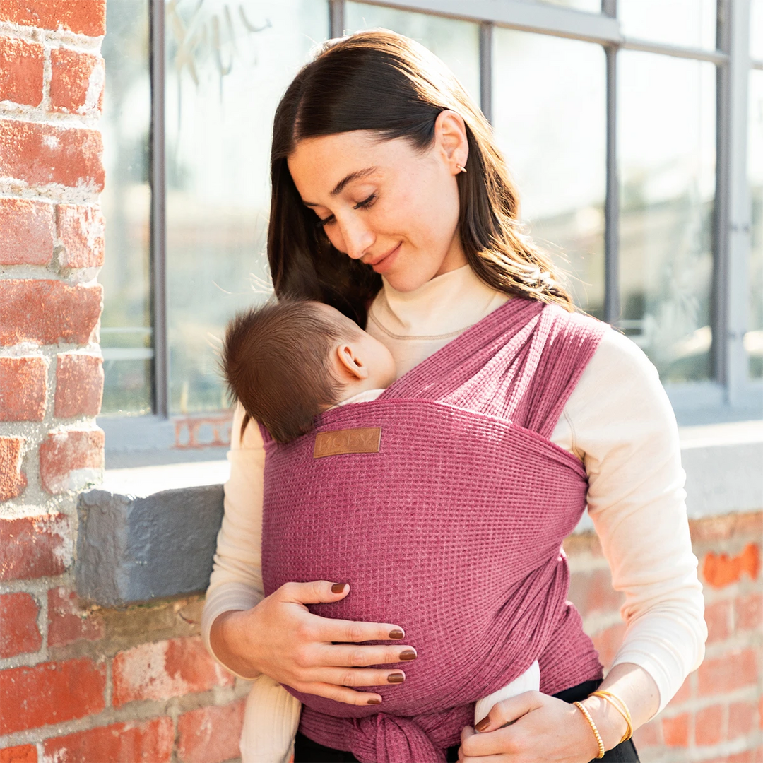mom wearing baby in waffle knit wrap in desert rose