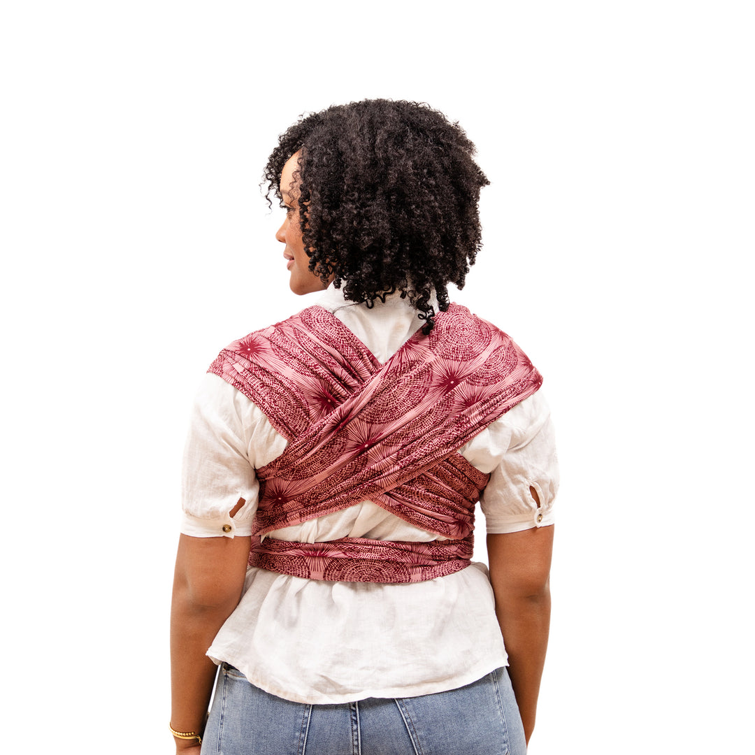 a back image of mom wearing the petunia and moby evolution wrap in sunbeam
