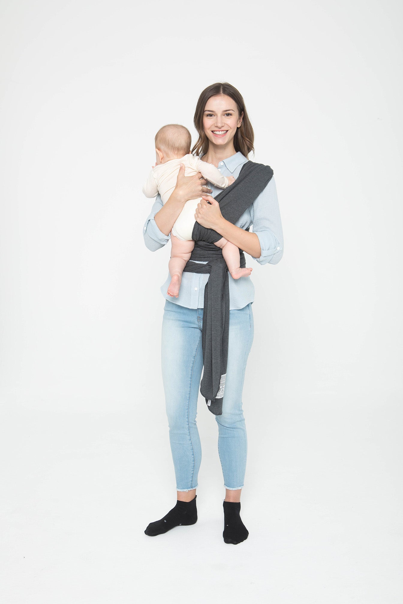 Image of mom guiding baby's foot under the shoulder strap closest to your body.