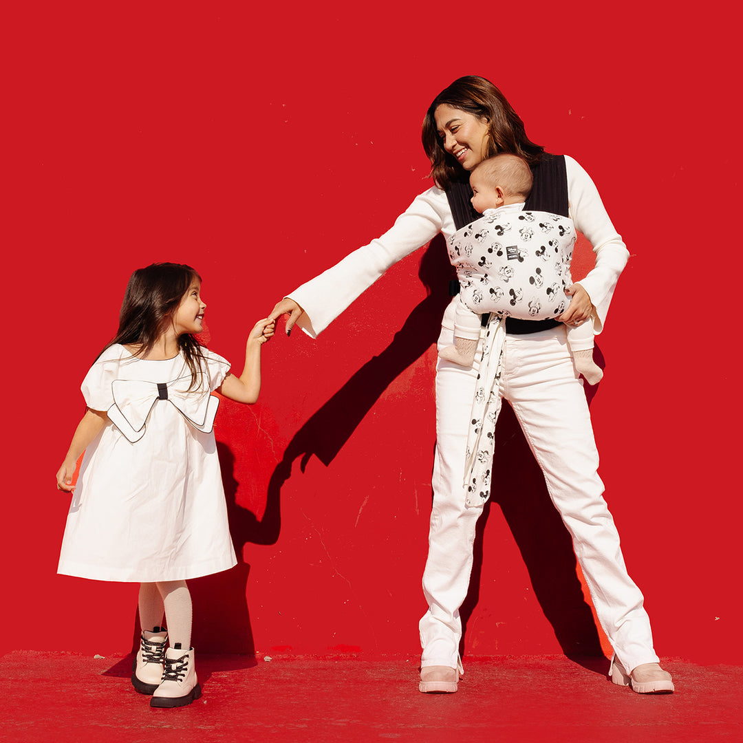 mom wearing baby in Easy-Wrap Carrier in Disney's Mickey Mouse & Minnie Mouse while playing with toddler girl