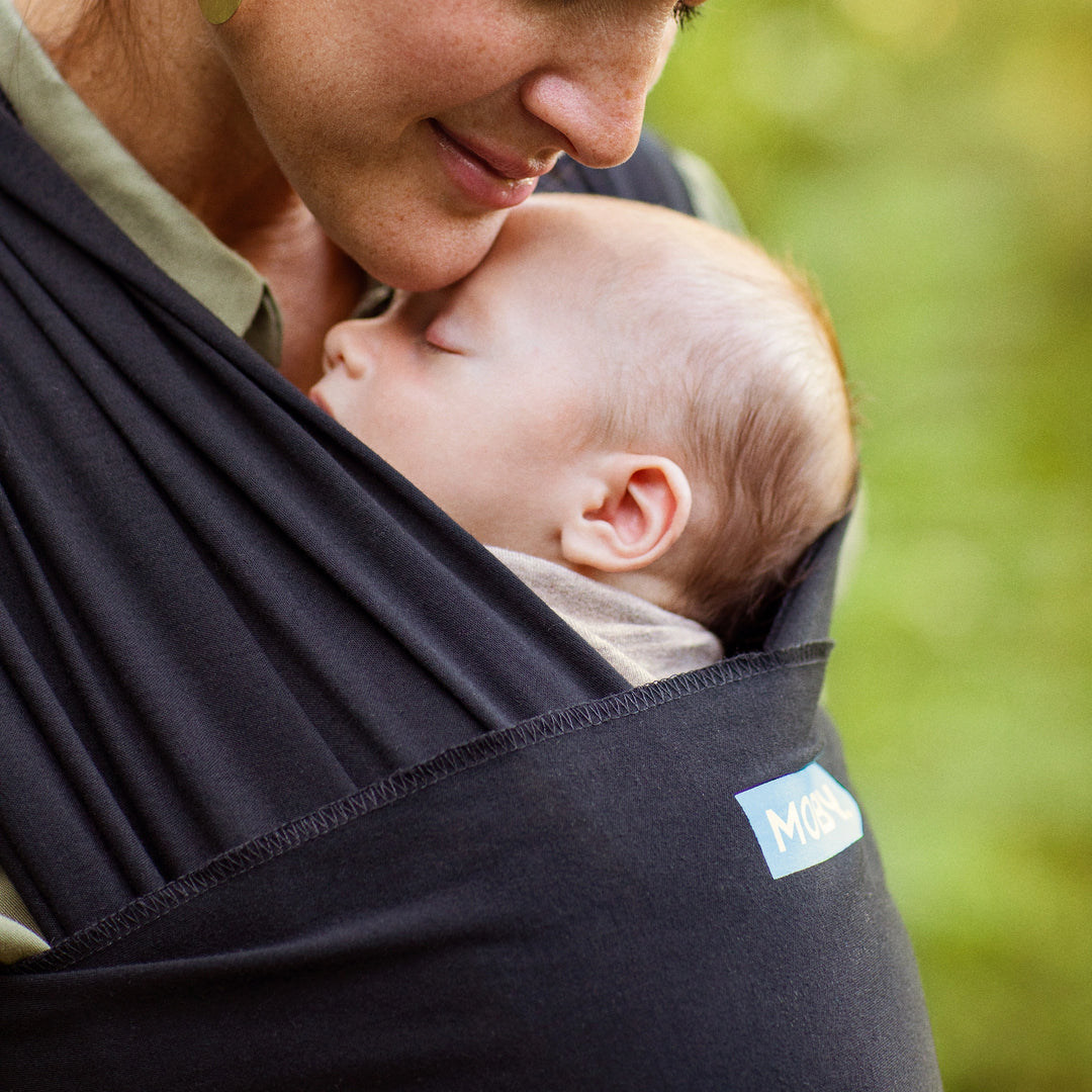 moby wrap shown supporting baby in ergonomic seated position worn chest to chest on female caregiver