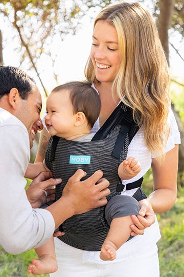 woman in white pants wearing her baby in a moby wrap