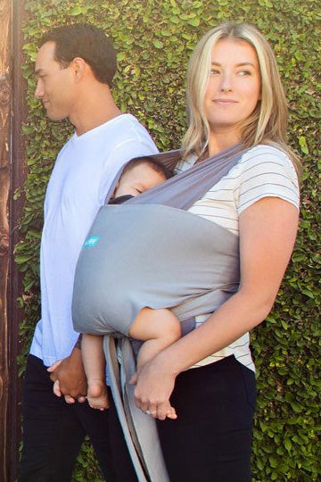 couple taking a walk outside wearing their baby in a moby wrap