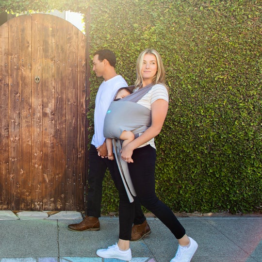 couple taking a walk outside wearing their baby in a moby wrap