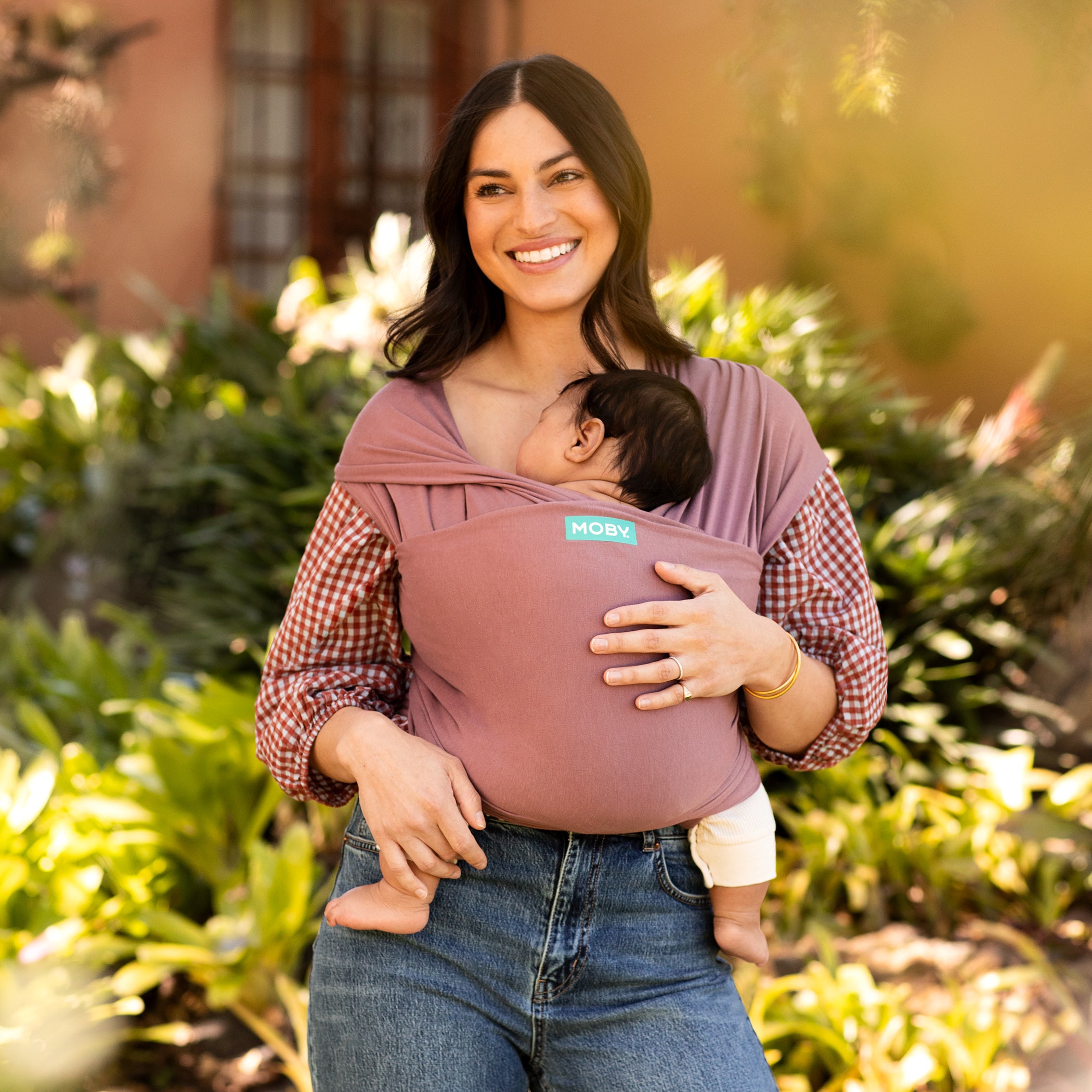 mom wearing infant in stretchy 70% viscose, 30% cotton blended baby wrap carrier in terracotta color