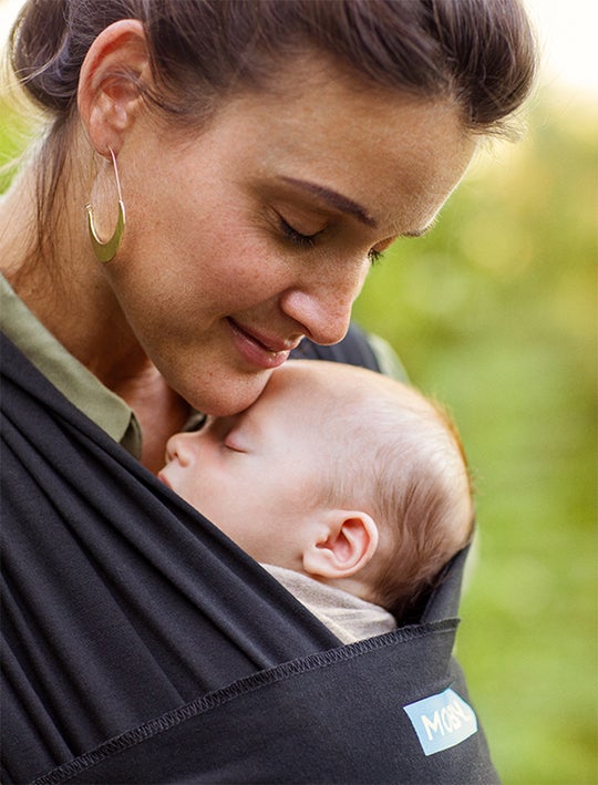 woman in the forest wearing her baby in a moby wrap - close up