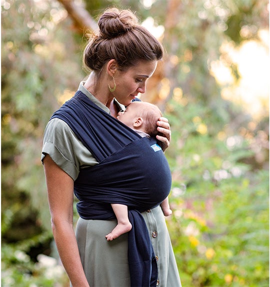 woman in the forest wearing her baby in a moby wrap