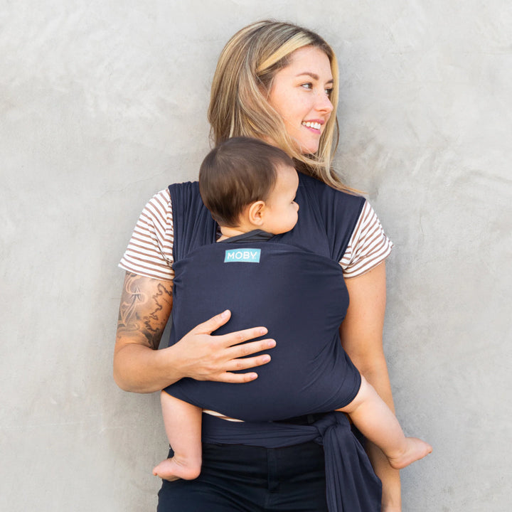 Mom wearing baby in Classic Wrap Baby Carrier in Deep Sea. 