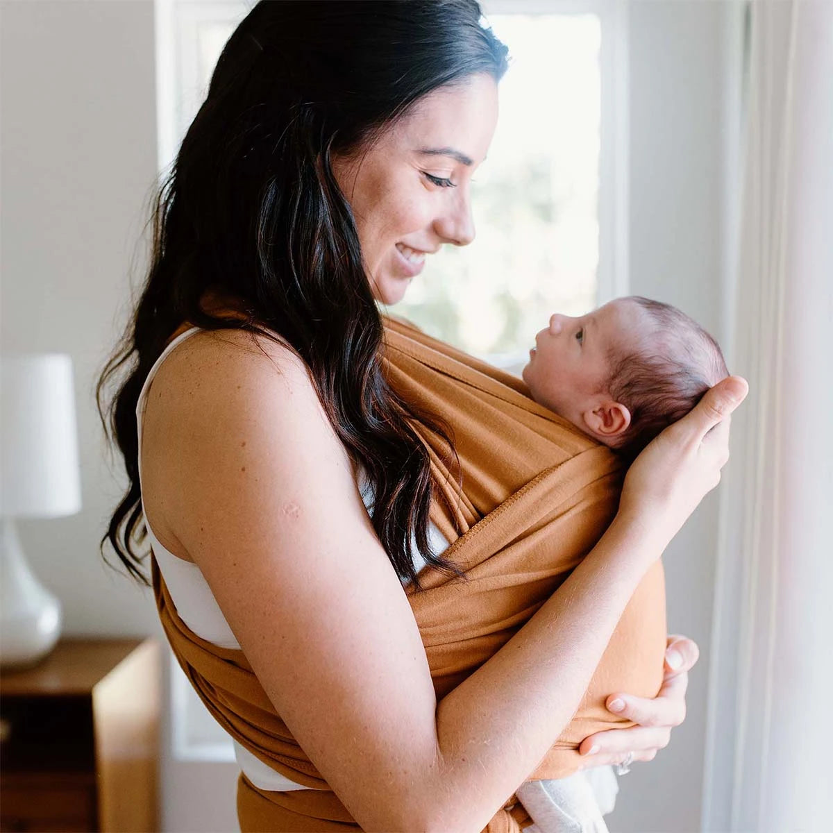moby wrap caramel shown with mom wearing newborn baby