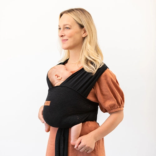 mom wearing baby in black eyelet easy wrap by petunia pickle bottom