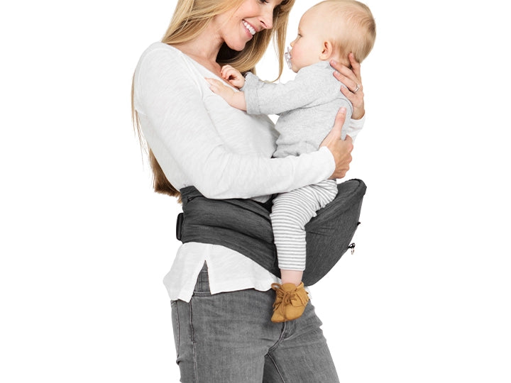 mom holding baby while wearing the hip seat carrier