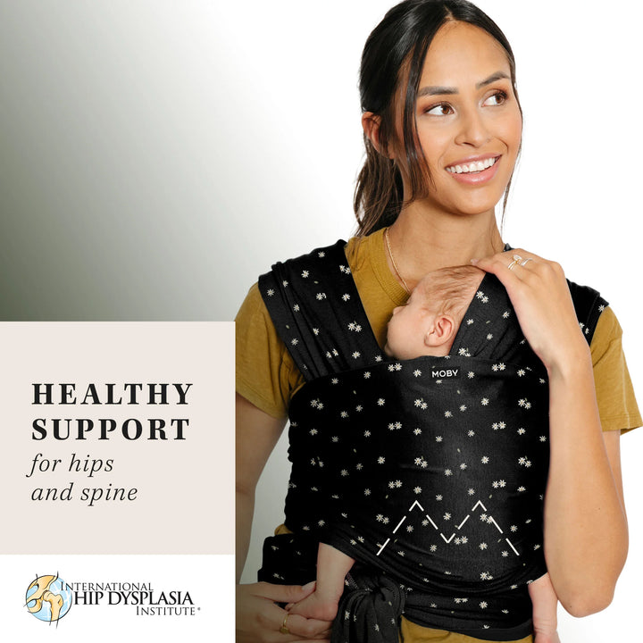 mom wearing baby in Classic Wrap Baby Carrier in Desert Daisy. healthy support for hips and spine from the international hip dysplasia institute.