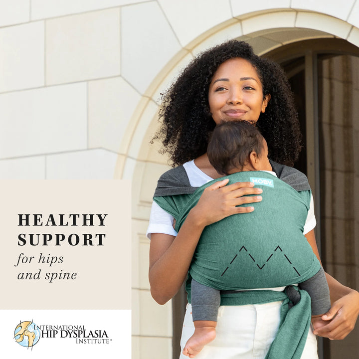 mom wearing baby in reversible wrap in jade grey. healthy support for hips  and spine by international hip dysplasia institute