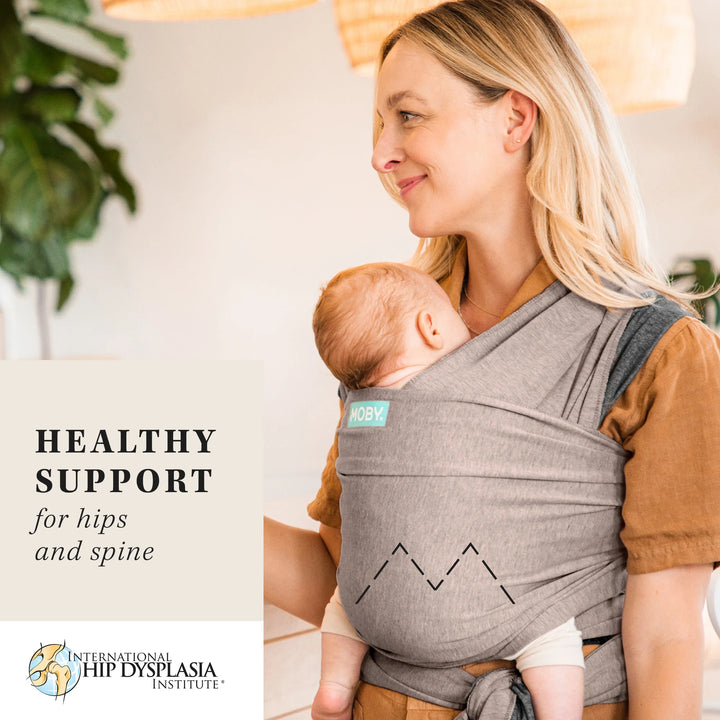 mom wearing baby in reversible wrap in taupe. healthy support for hips  and spine by international hip dysplasia institute