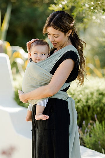 woman in black dress wearing her baby in a moby wrap