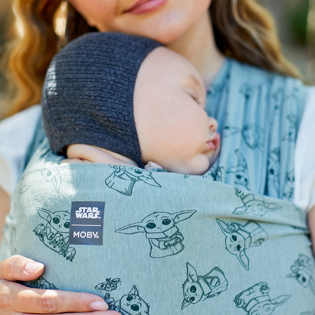 Mom wearing baby in Moby Featherknit Wrap in Playful Padawan